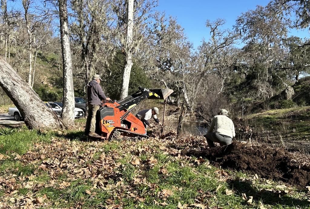Using the skip loader to pull the fence posts